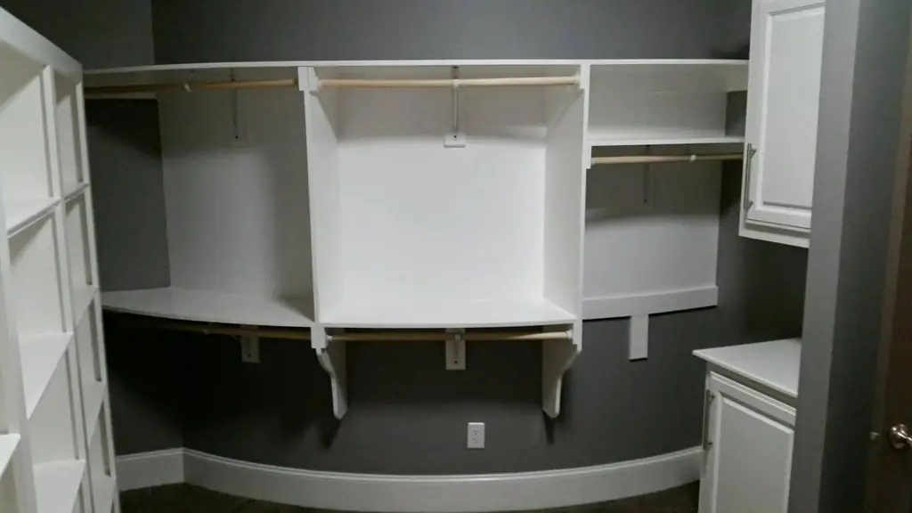 A white built-in walk-in closet with shelving fit flush to the walls
