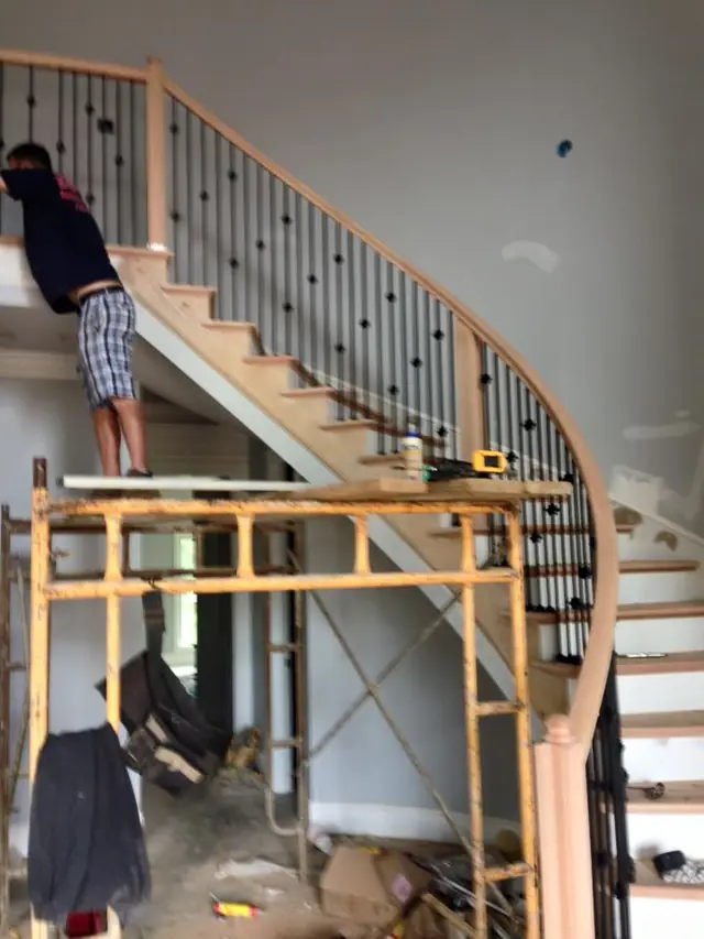 A carpenter on scaffold fitting the rail on the same curved stair