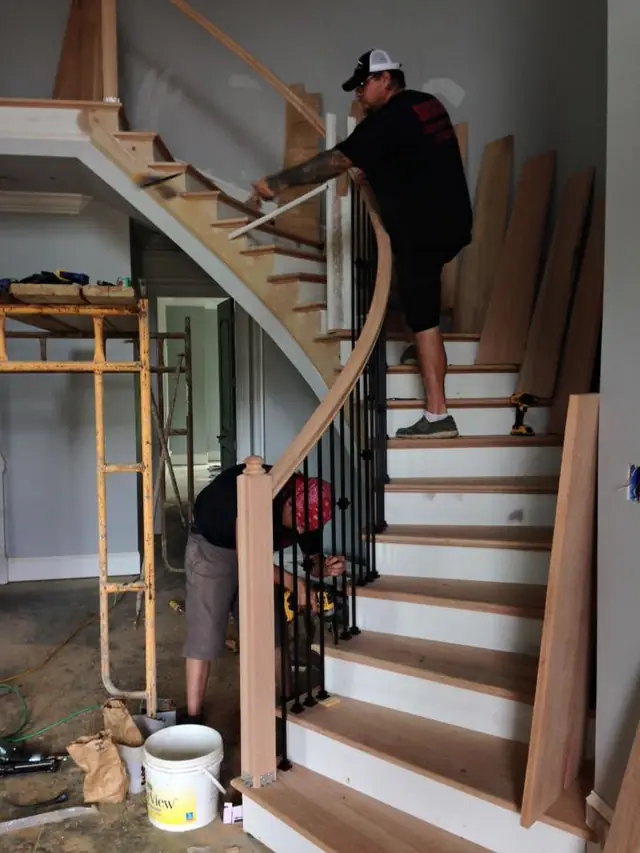 Two carpenters fitting treads on a curved stair