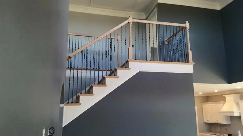 A straight staircase with an oak rail and iron balusters